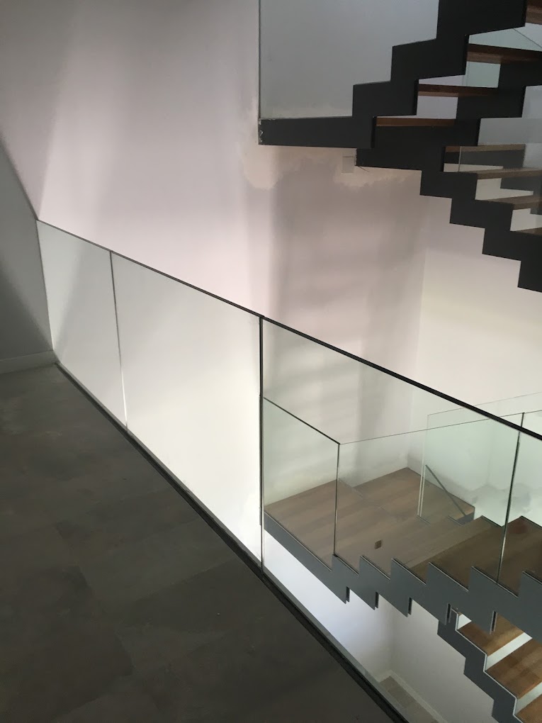 Barandilla de vidrio junto a una escalera metálica